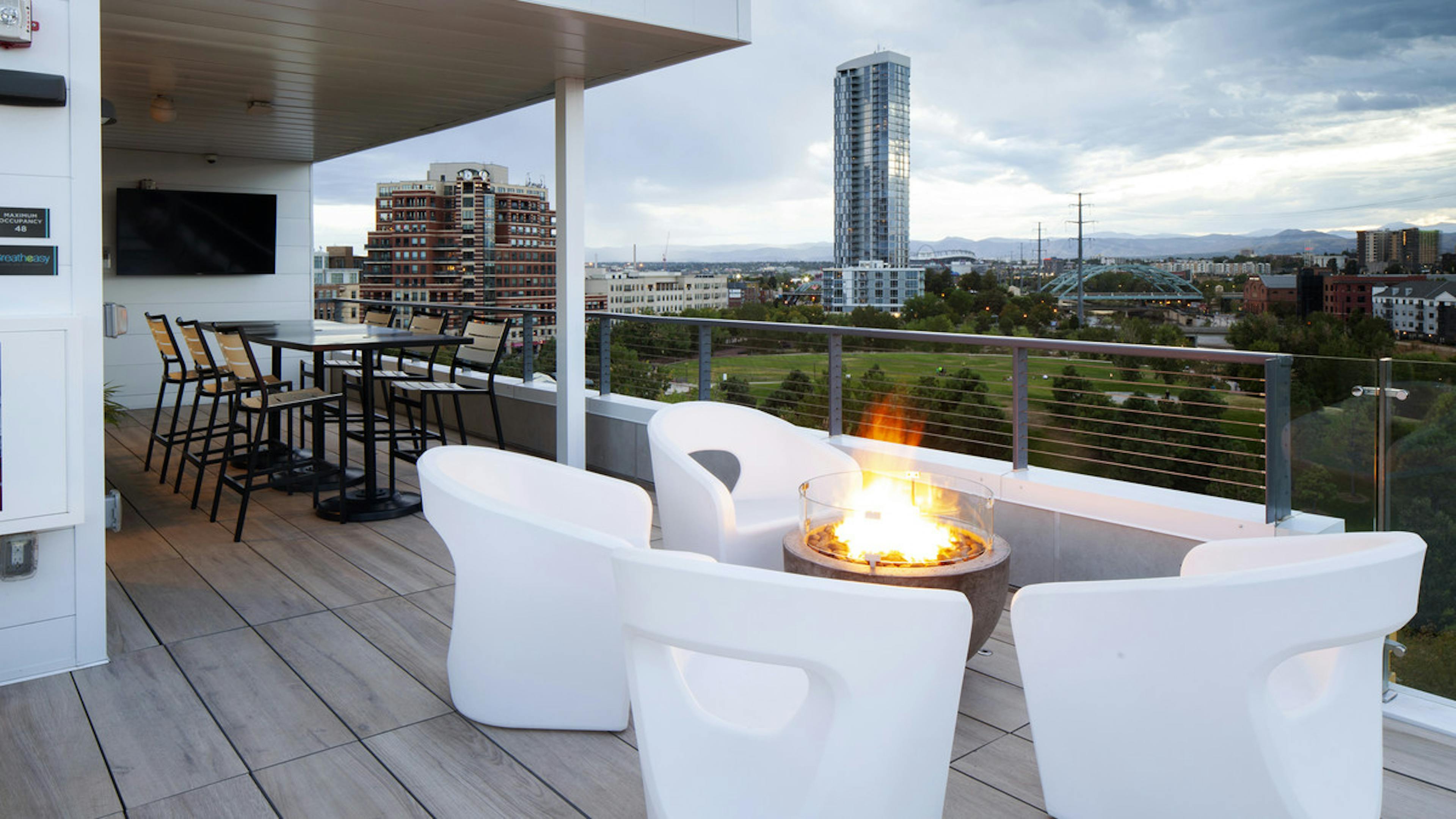 An exterior view of AMLI Riverfront Green roof top deck with fire pit and furniture and mountain view and skyscraper views