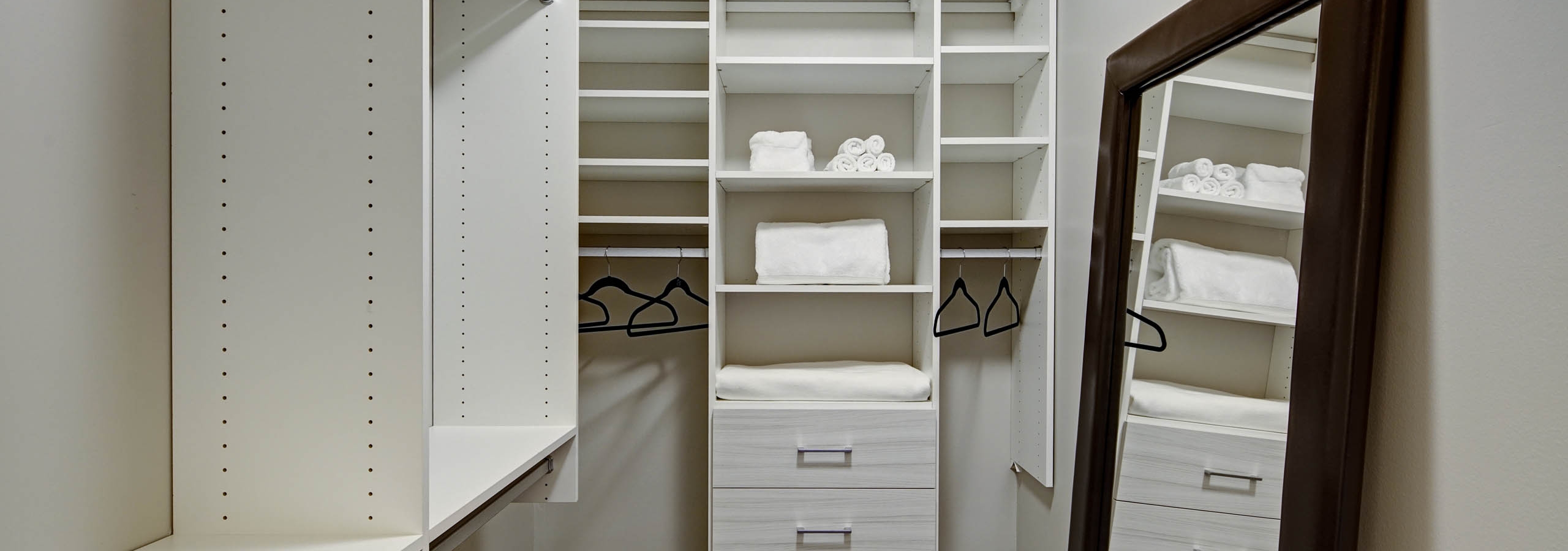 AMLI River North apartment walk in closet with built in shelving and a large framed mirror leaning against an empty wall