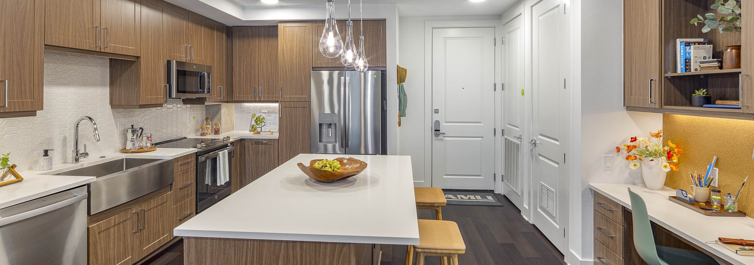 AMLI Branch Park kitchen with white quartz island and wood cabinets and stainless steel appliances and farmhouse sink