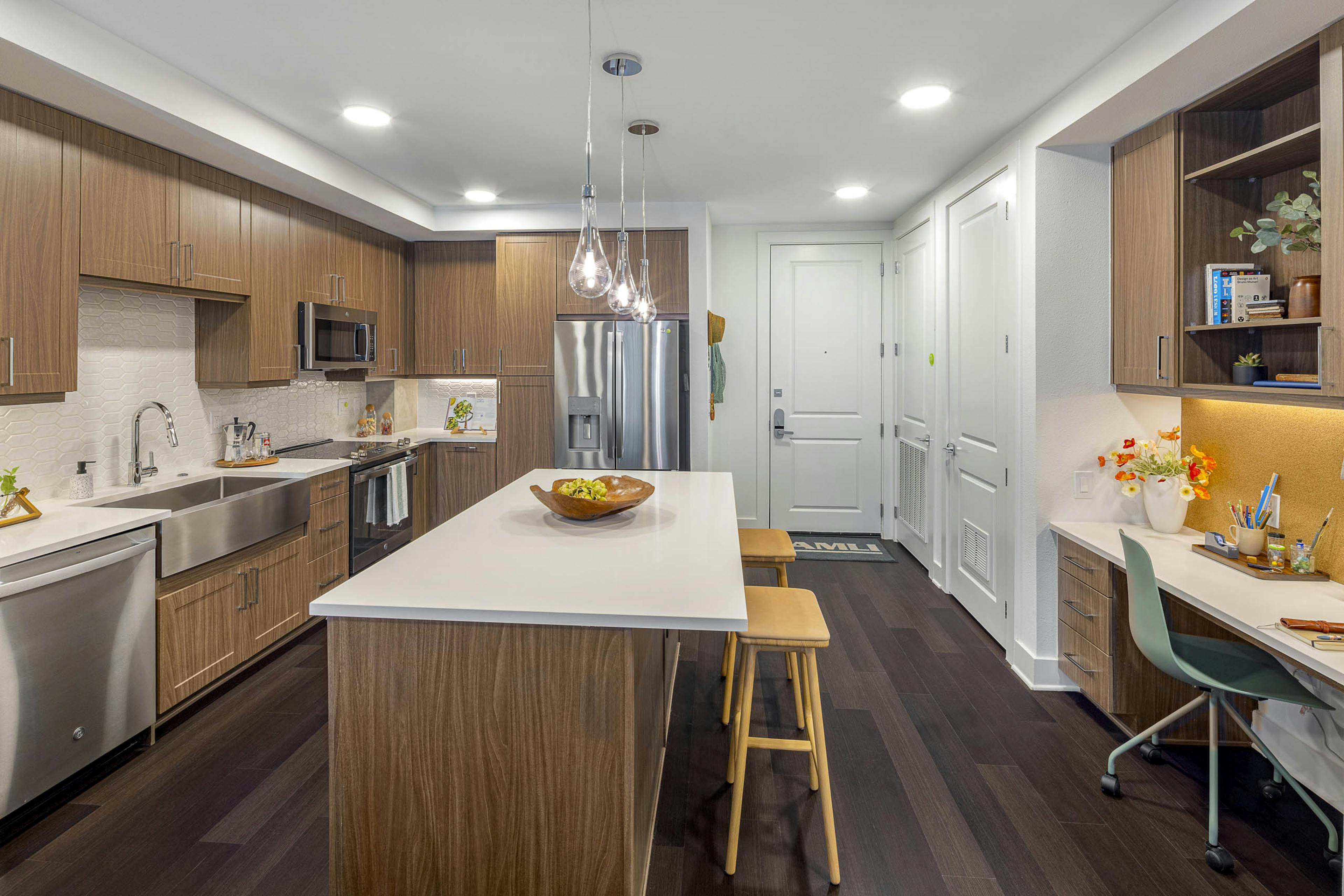 AMLI Branch Park kitchen with white quartz island and wood cabinets and stainless steel appliances and farmhouse sink