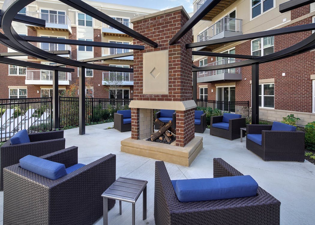 Exterior view of courtyard fireplace with several blue cushioned sitting areas at AMLI Deerfield apartment community