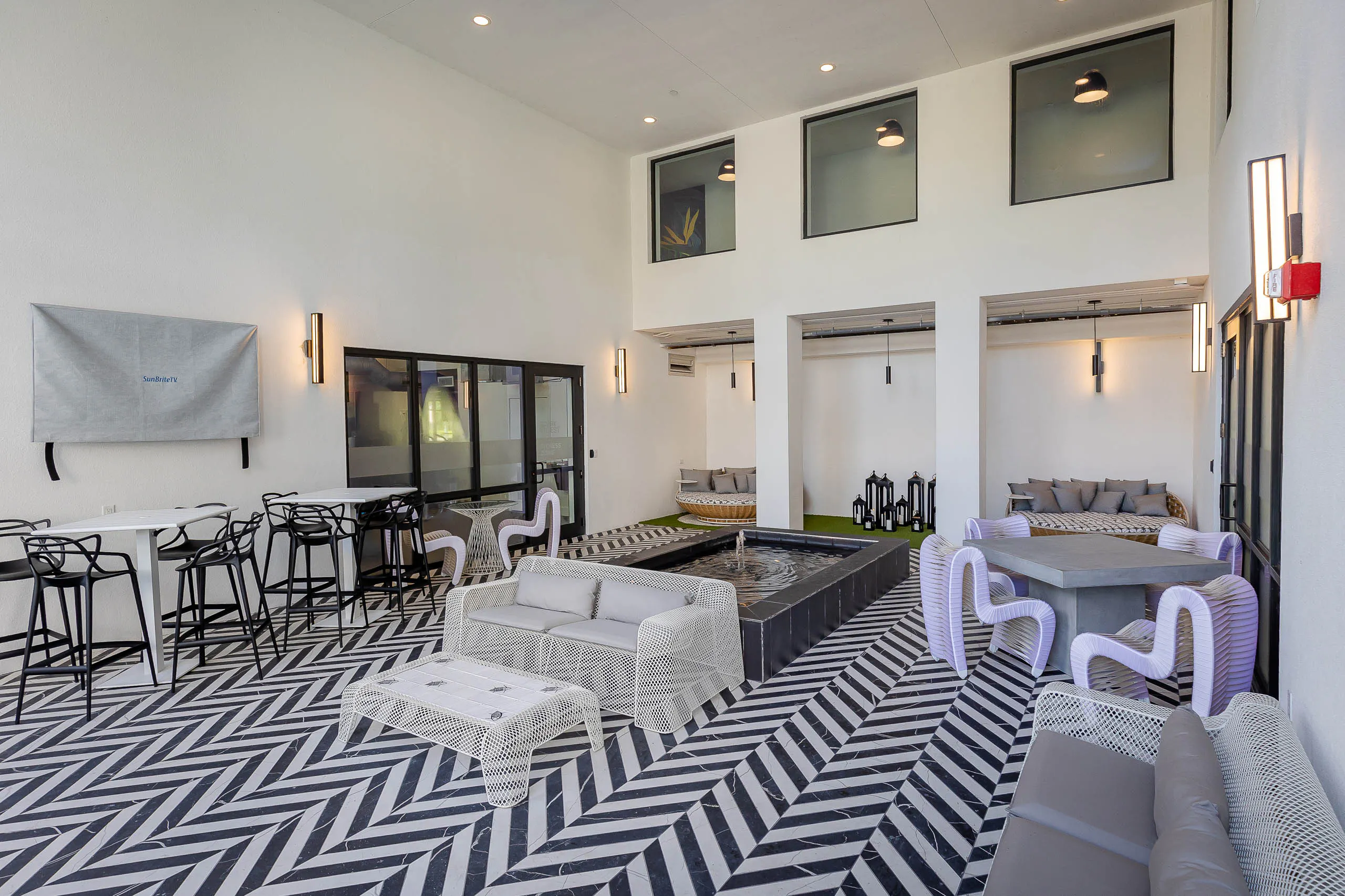 Pool lounge at AMLI Park West apartments with black and white tiled floors and wired outdoor furniture and center fountain 