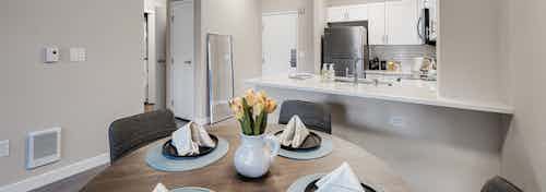 Interior view of round kitchen table set for 4 and white kitchen with stainless appliances at AMLI Bellevue Park apartments