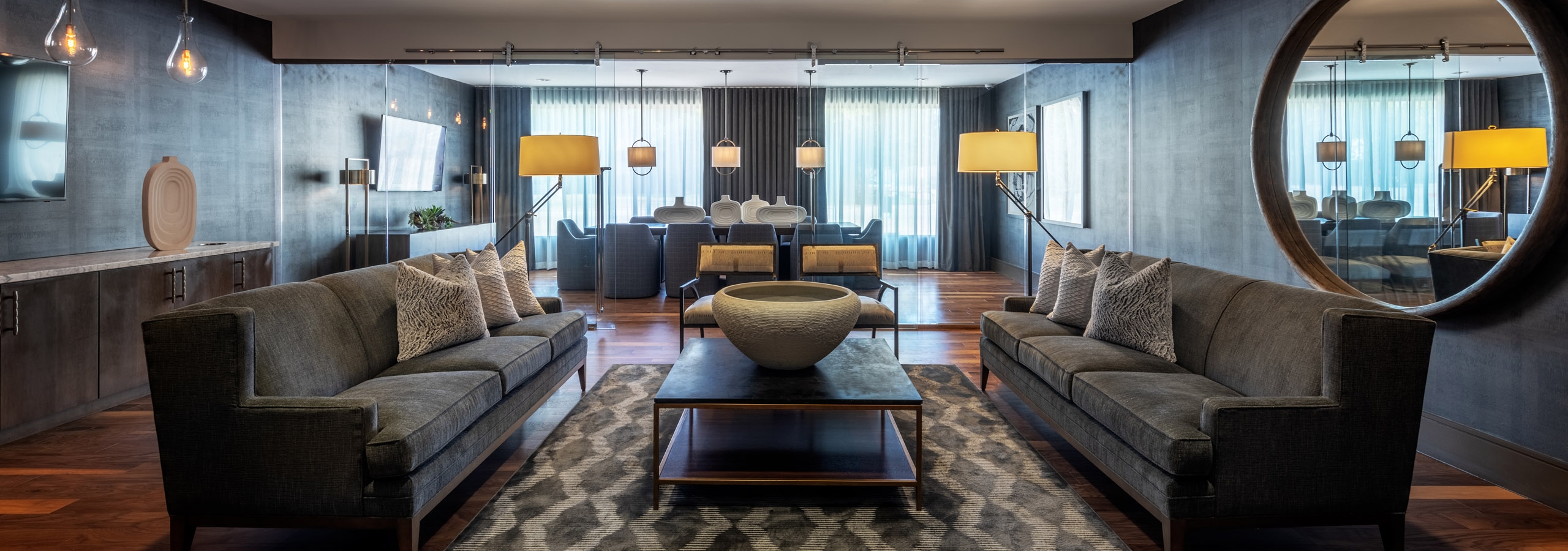 AMLI Grapevine apartment building conference room with hardwood floor and gray lounge seating and a large gold round mirror