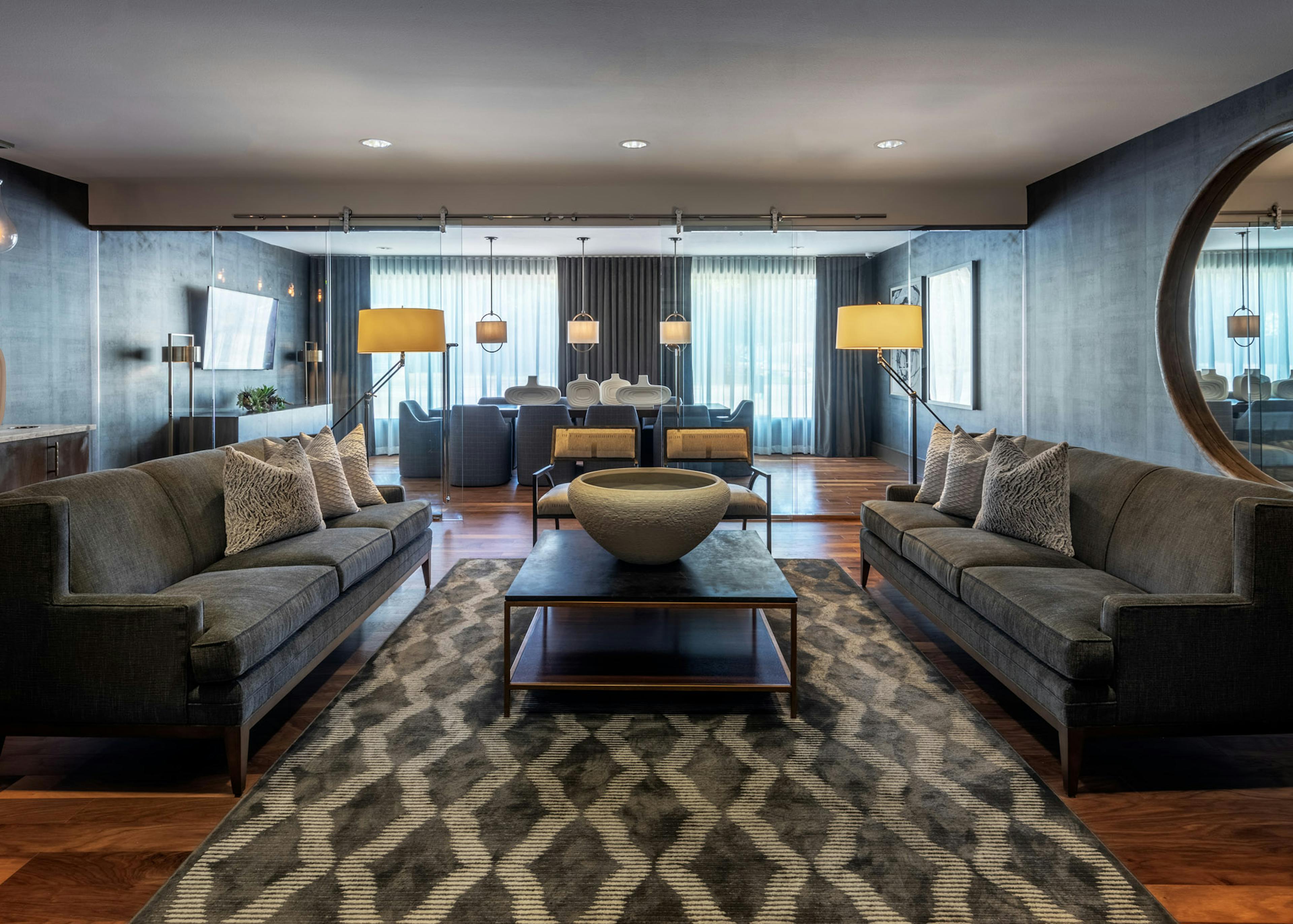 AMLI Grapevine apartment building conference room with hardwood floor and gray lounge seating and a large gold round mirror