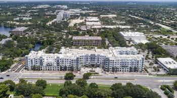 Aerial view of AMLI Park West apartment building with buildings and trees in the rear distance under a cloudy sky