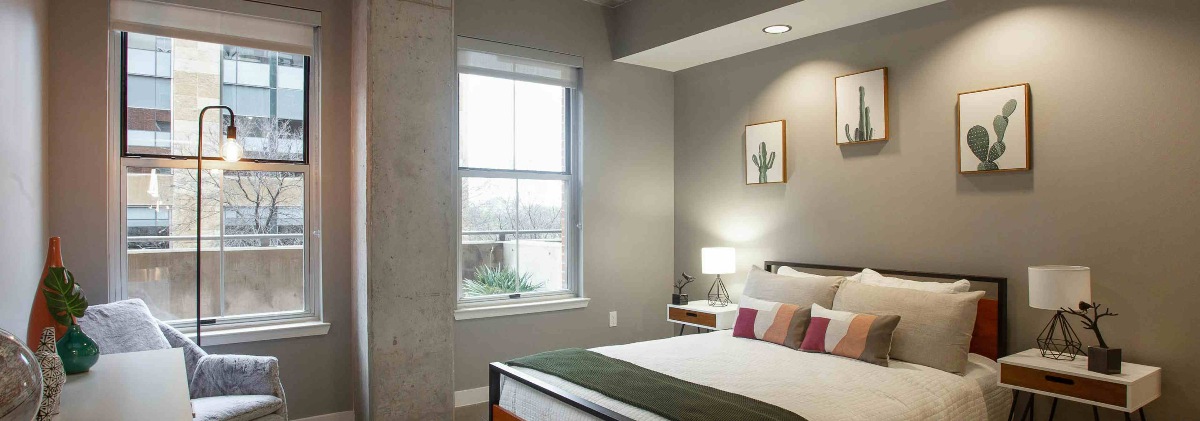 AMLI Downtown bedroom with grey walls and a comfy white bed in front of two large windows with a bright daytime view