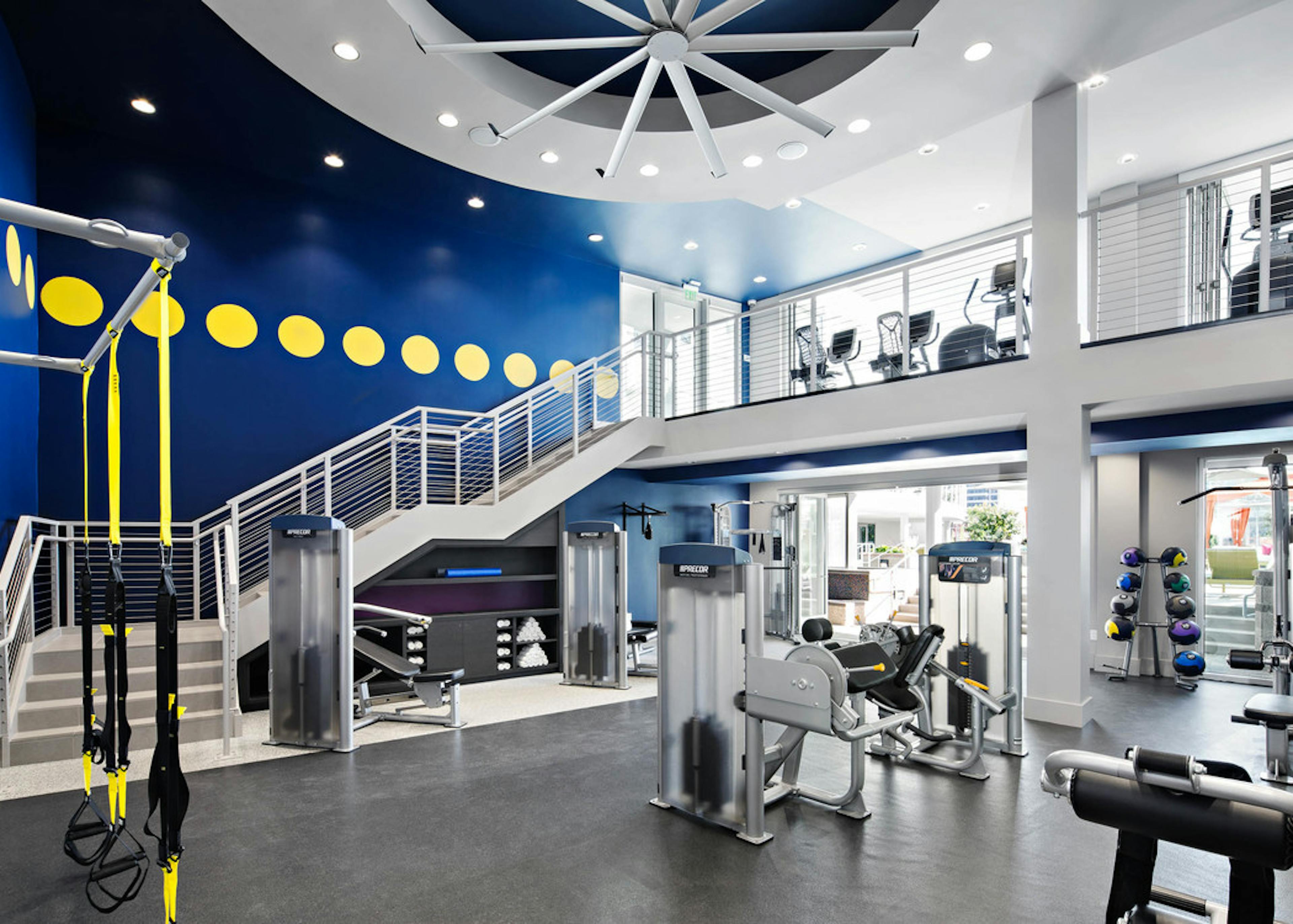Interior of two-story fitness center at AMLI Lex on Orange apartments with TRX system and medicine balls and cardio machines