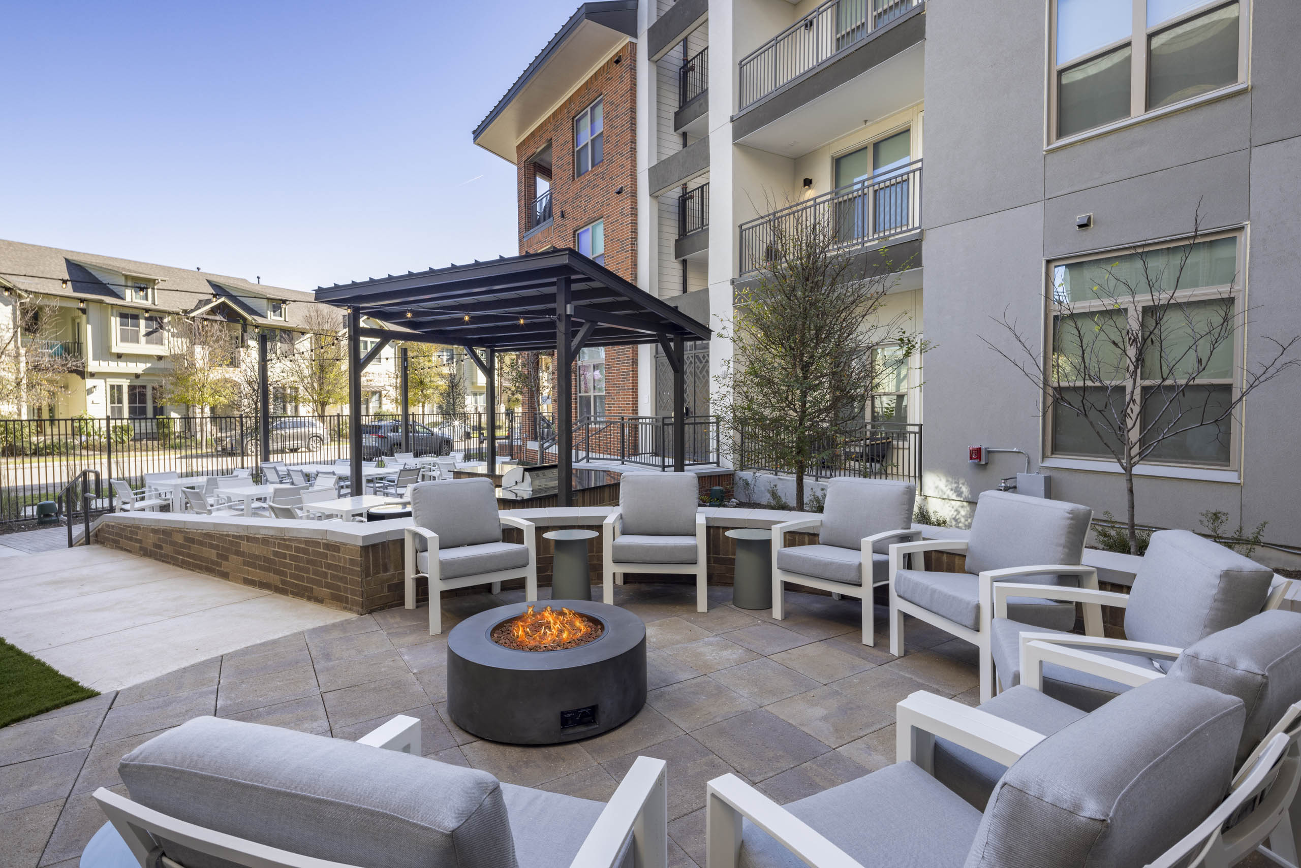 Daytime view of AMLI Branch Park courtyard featuring an outdoor firepit surrounded by white chairs with gray cushions