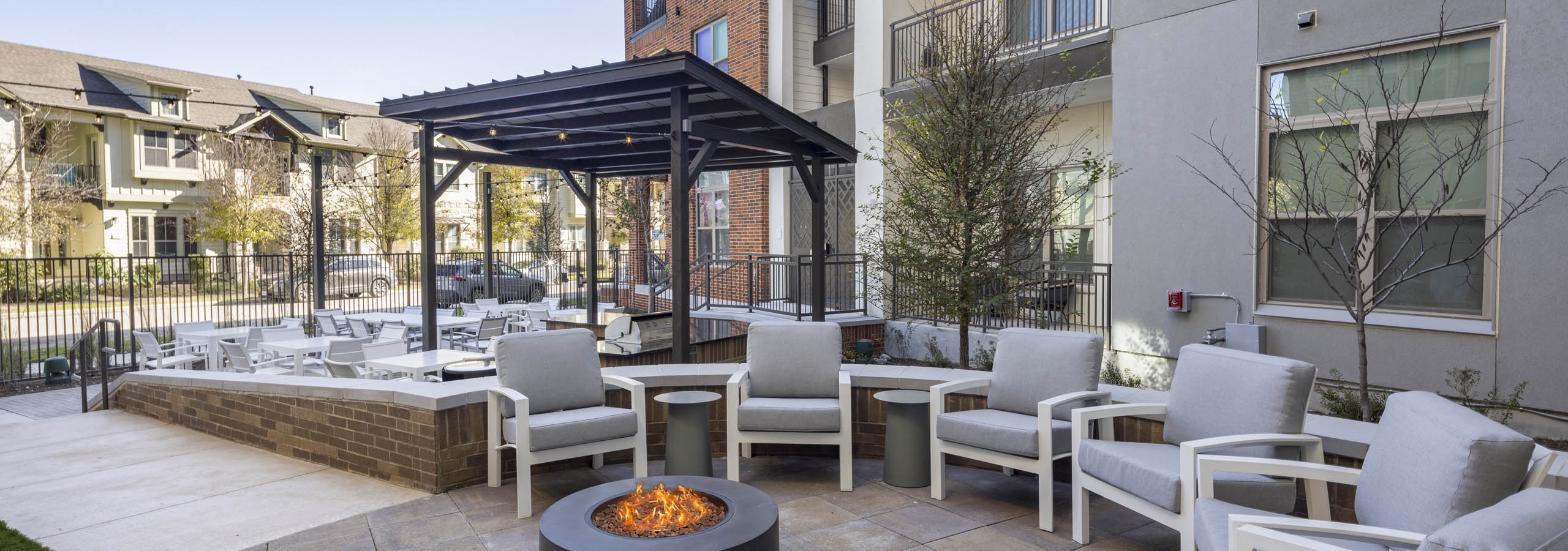 Daytime view of AMLI Branch Park courtyard featuring an outdoor firepit surrounded by white chairs with gray cushions