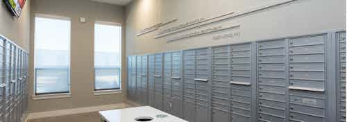 Interior of AMLI on Aldrich mailroom with grey mailboxes along neutral colored walls with light flooring and bright windows