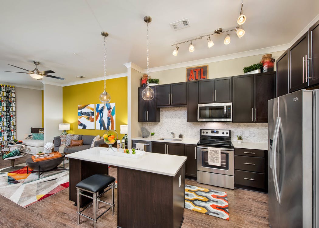 AMLI Buckhead kitchen with dark wood cabinets and quartz countertops and an island with living space visible in background