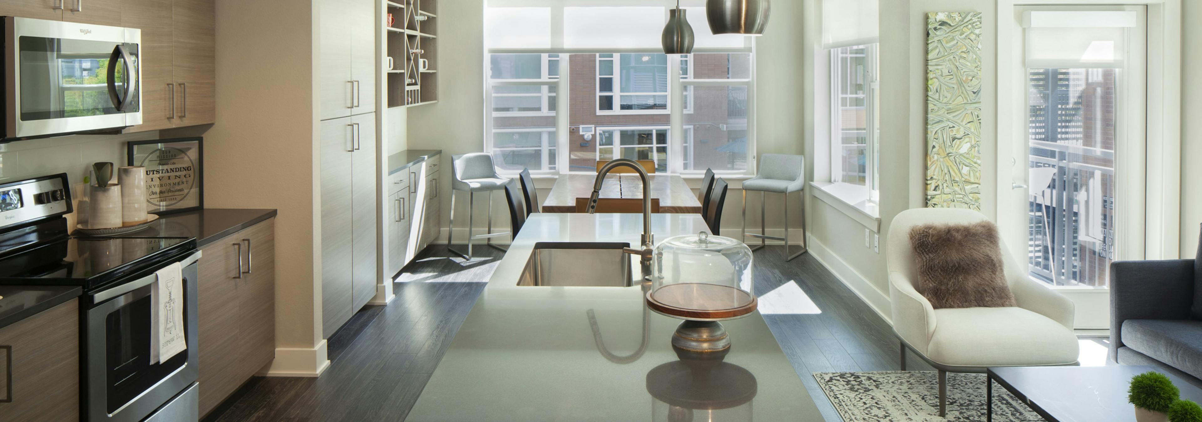 Interior view of AMLI Riverfront Green apartment kitchen and living room with dining room table and view of patio door