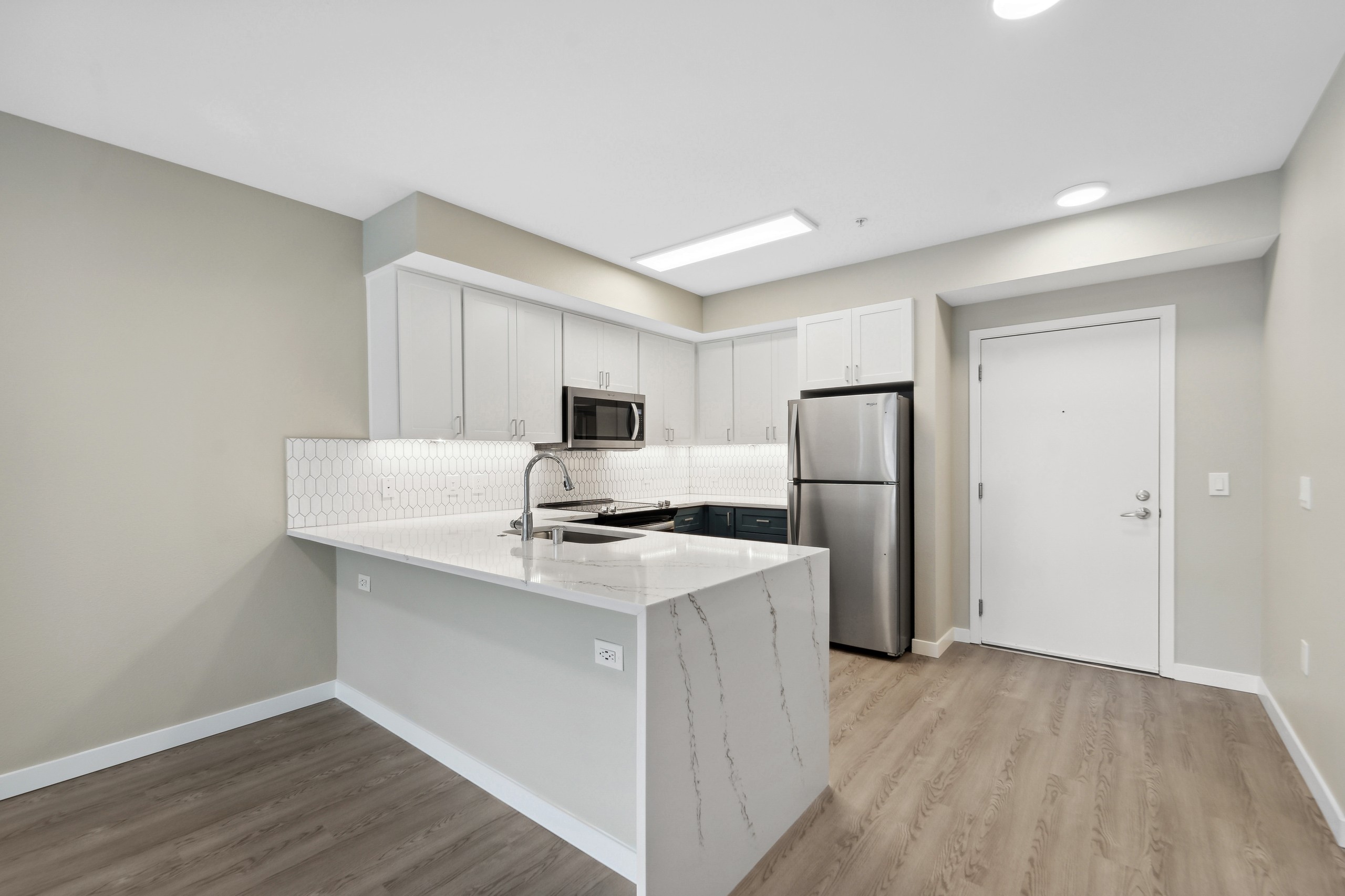 Interior view of a kitchen at AMLI 535 with white quartz countertop and cabinets and stainless steel appliances