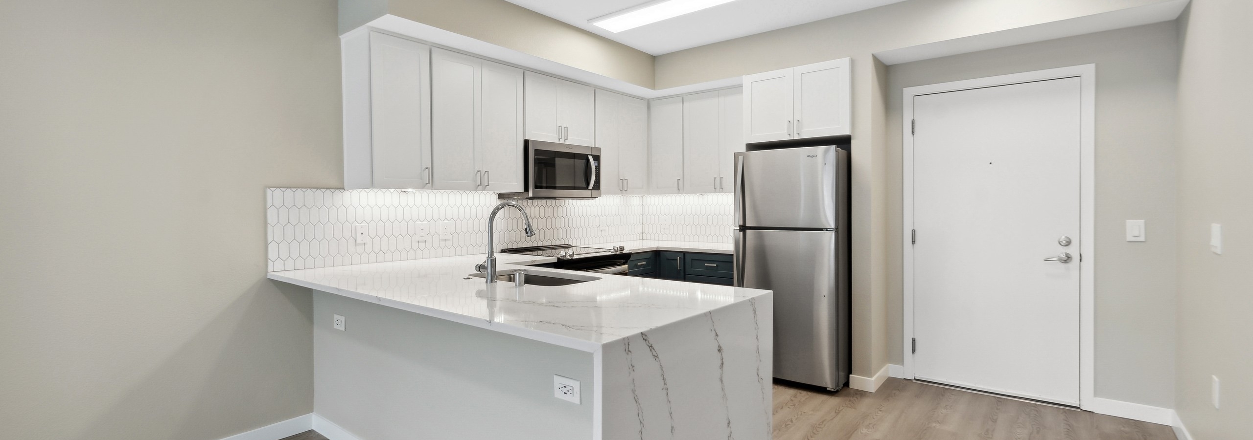 Interior view of a kitchen at AMLI 535 with white quartz countertop and cabinets and stainless steel appliances