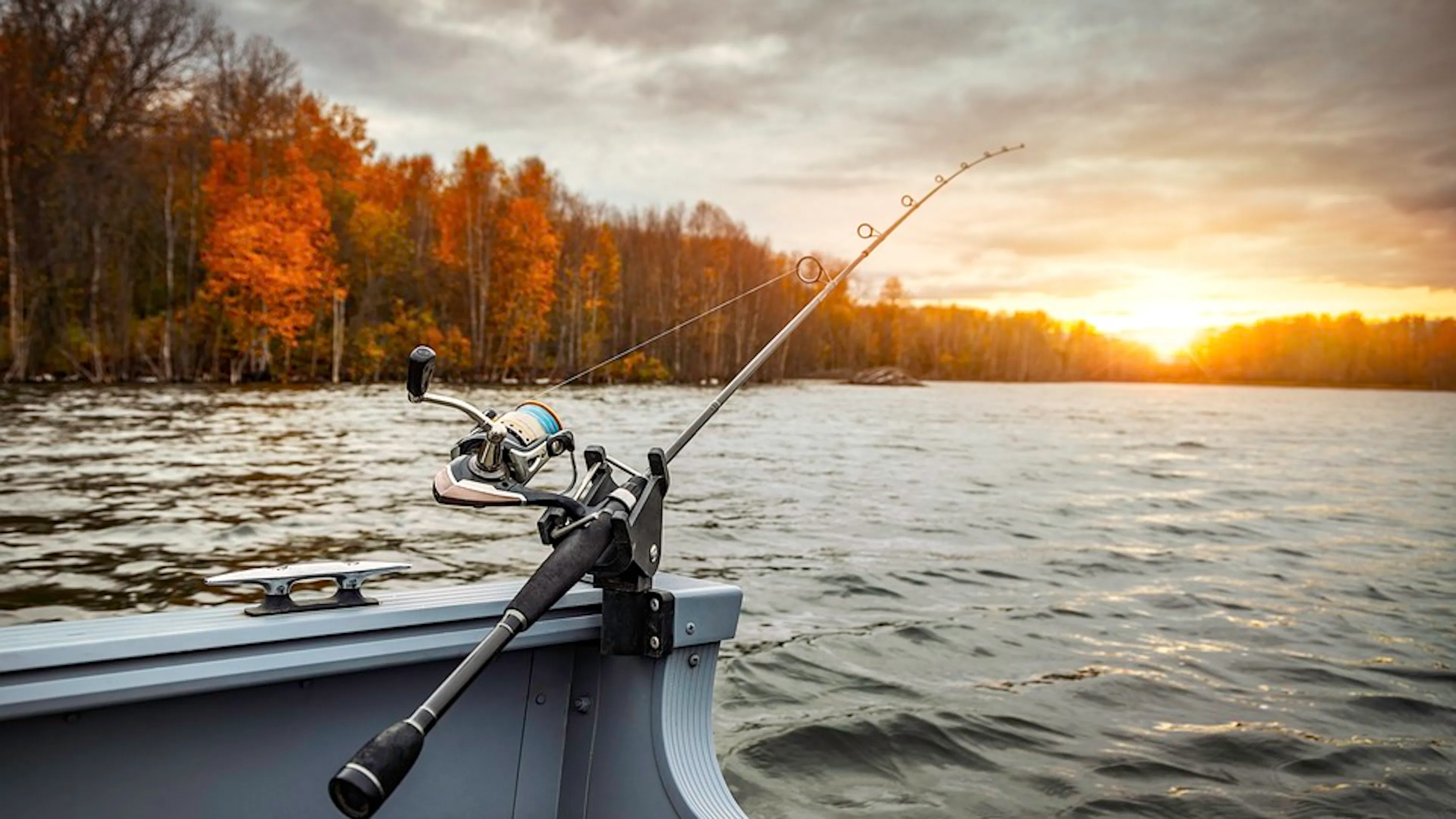 A close up of a fishing rod attached to a boat over a lake