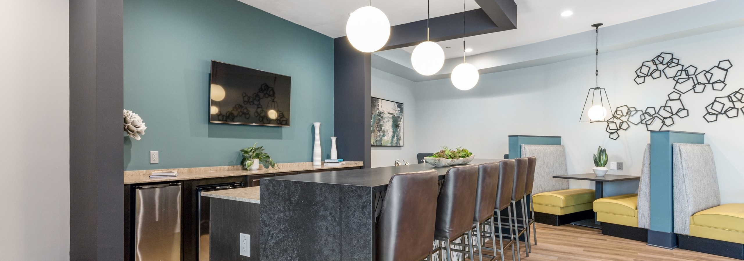 Resident serving kitchen in clubroom at AMLI Parkside apartments with gray serving counter and brown leather stools