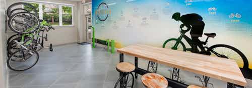 AMLI Buckhead bike storage and repair room with bikes stored vertically and a wooden table in front of a bicycle shadow mural