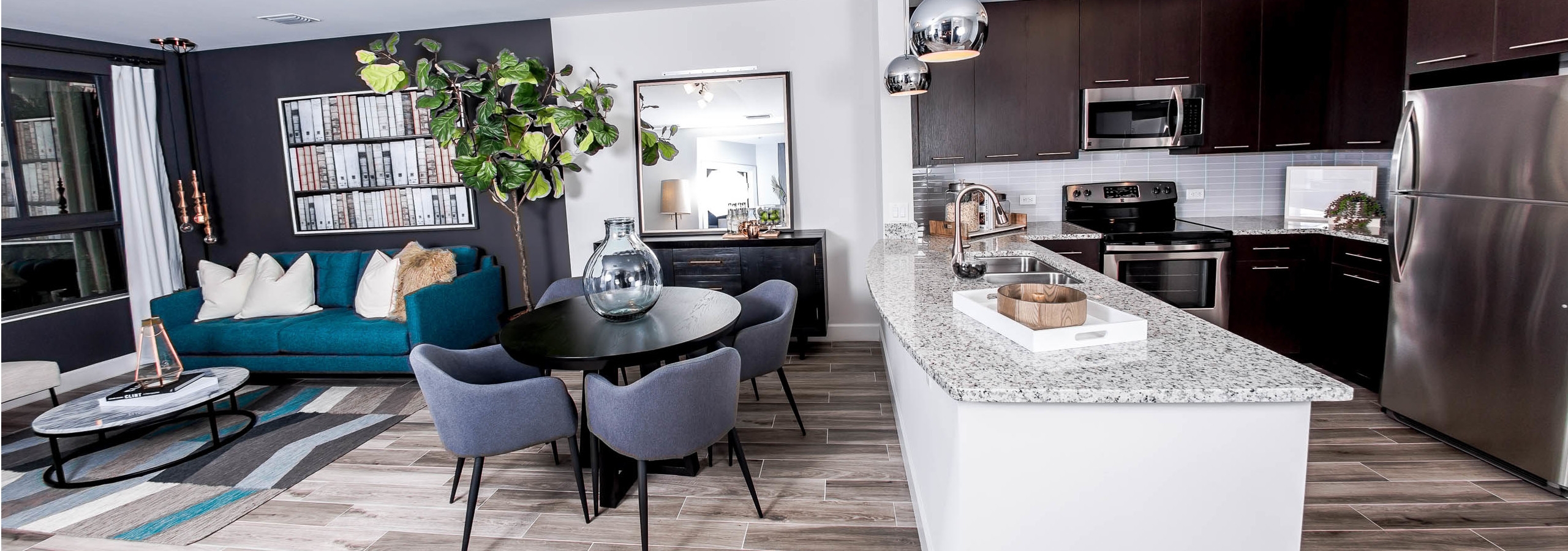 An AMLI Joya apartment contemporary living area and kitchen with stainless steel appliances and dark cabinetry