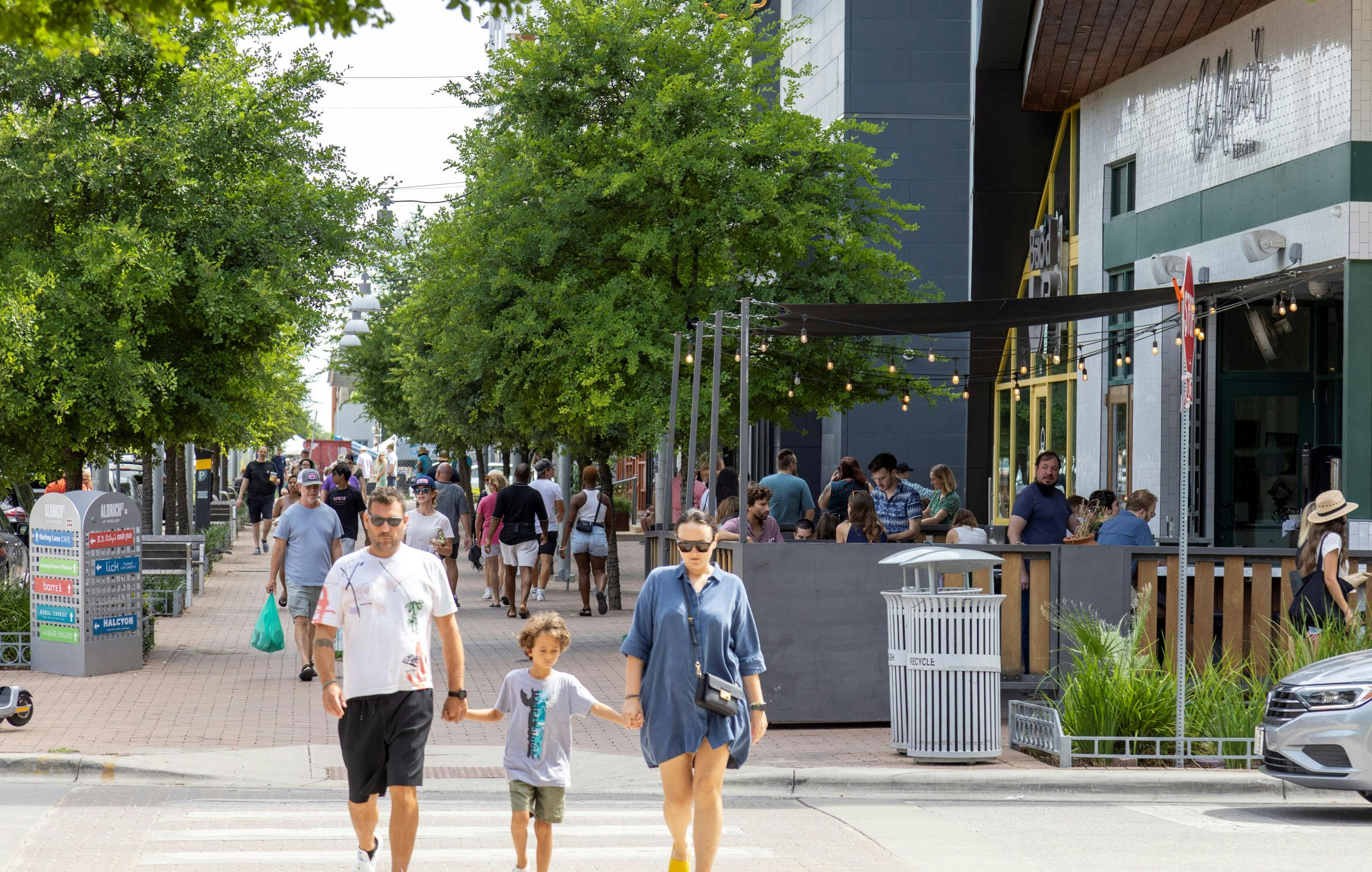 Street in Muller shopping district filled with people walking tree lined street on brick sidewalk