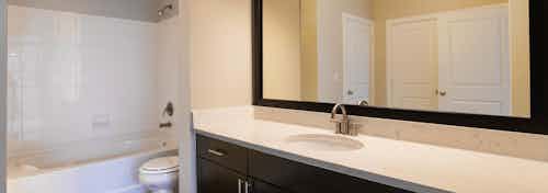 Redesigned bathroom at AMLI Inverness apartments with white granite counter top and large mirror with espresso wood framing