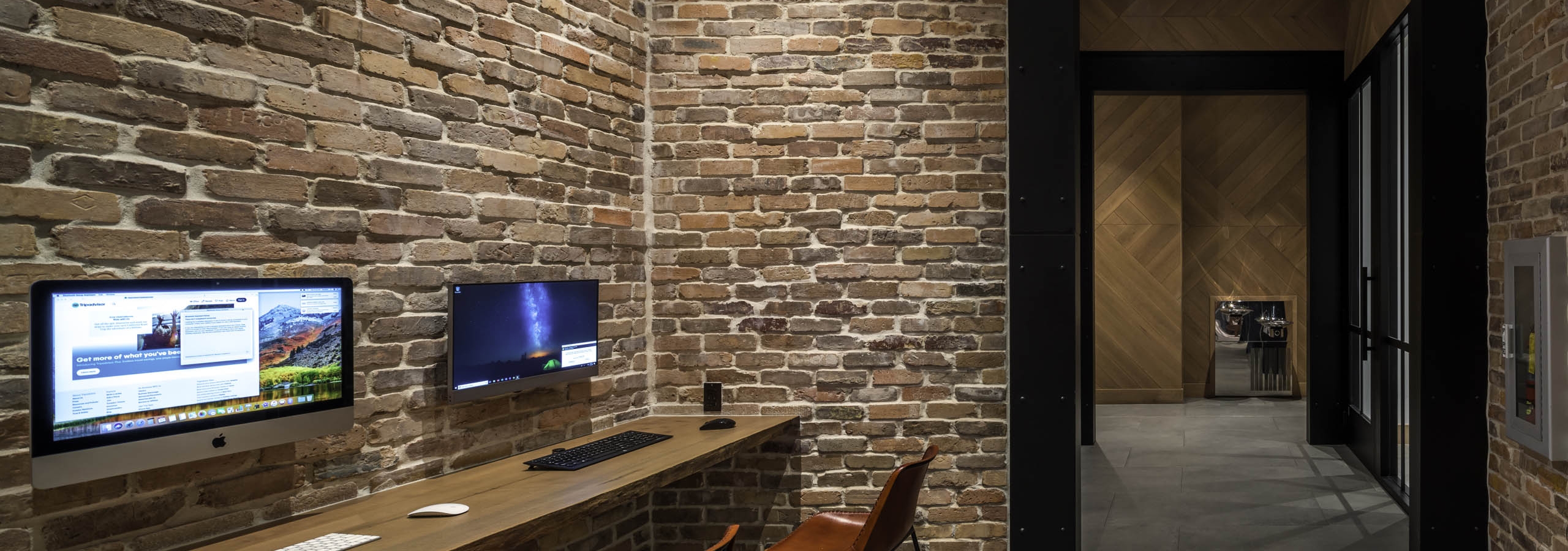 AMLI Midtown 29 business center with brick walls and wood counter with computer monitors and view of hall with wood wall