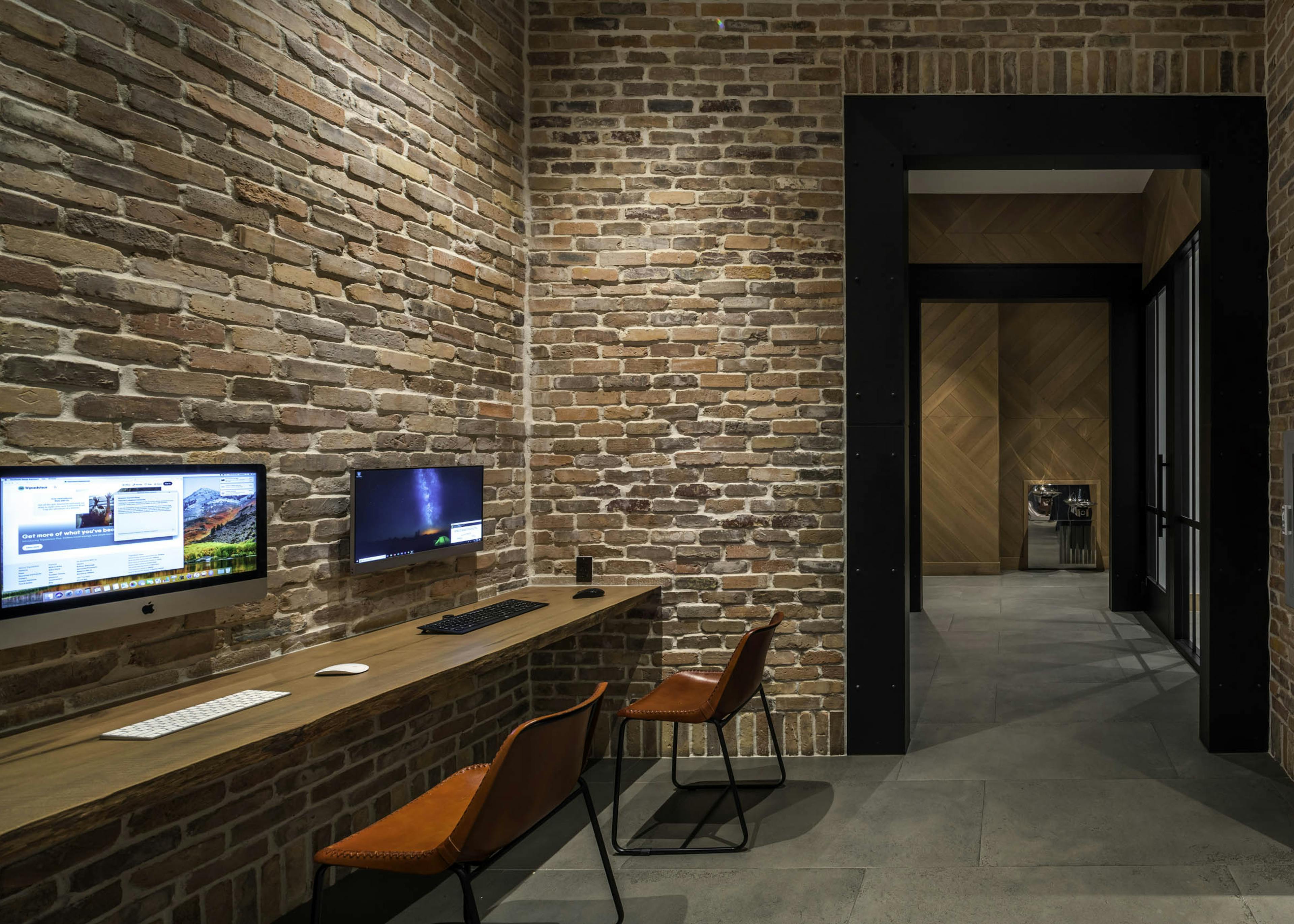 AMLI Midtown 29 business center with brick walls and wood counter with computer monitors and view of hall with wood wall