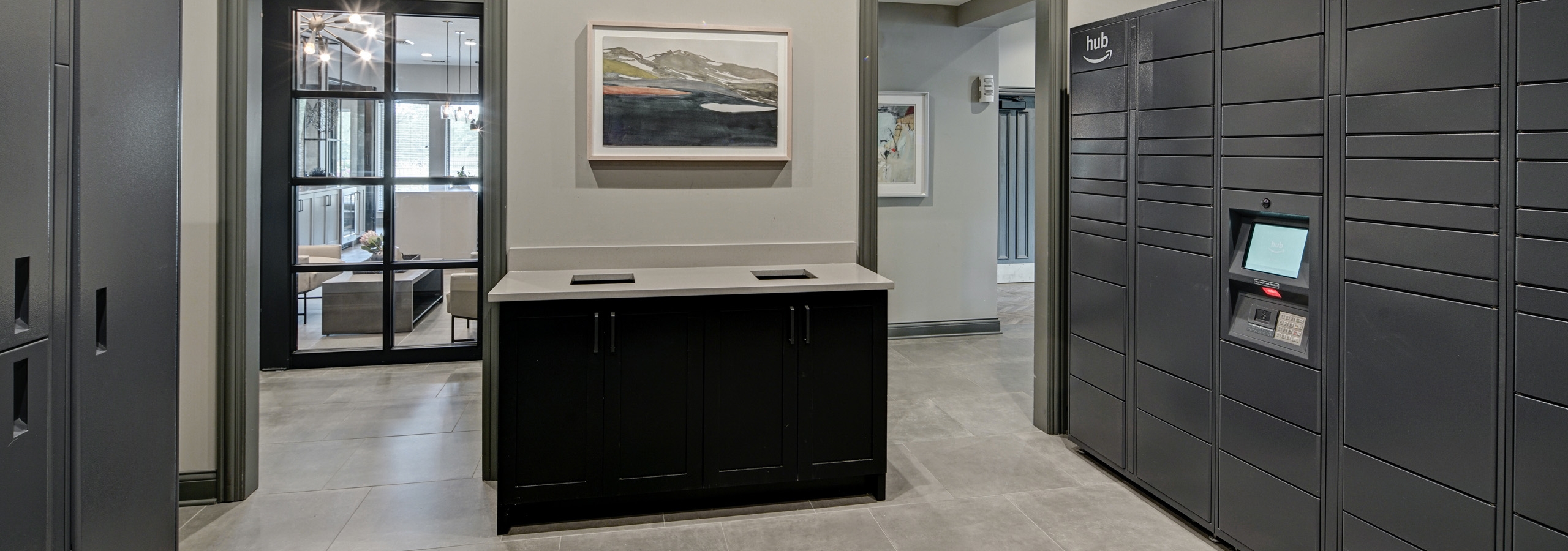 Gray Amazon Hub package lockers lining walls of room at AMLI at Seven Bridges apartments with 2 doorways into main clubhouse
