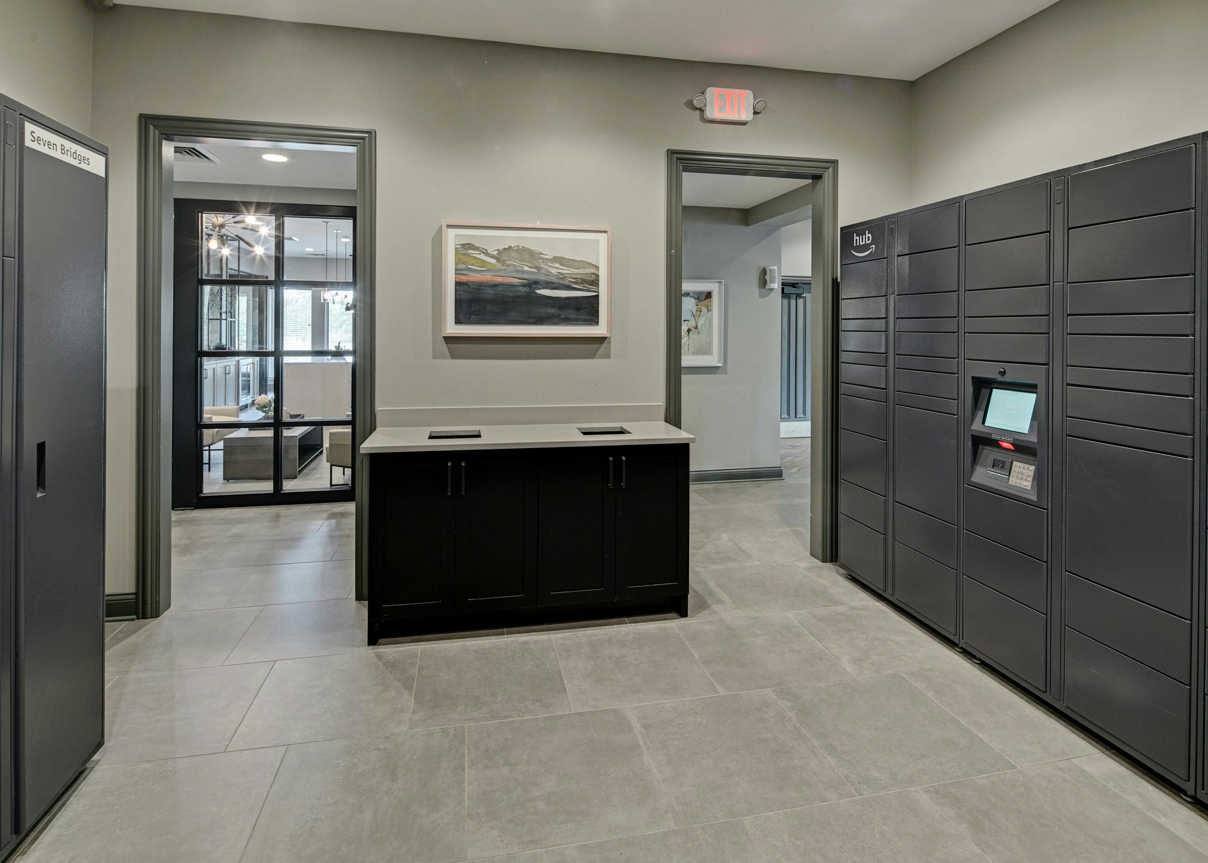 Gray Amazon Hub package lockers lining walls of room at AMLI at Seven Bridges apartments with 2 doorways into main clubhouse