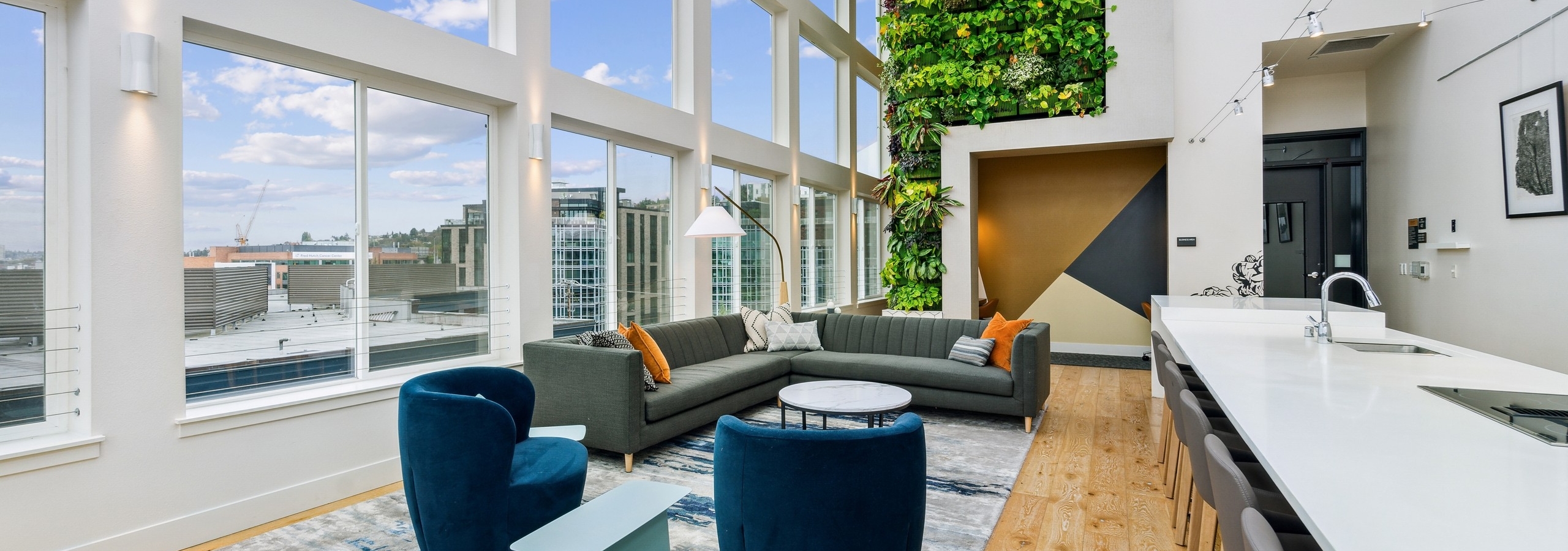 Solarium at AMLI South Lake Union with a long bar with chairs and couch seating as well as a large plant wall in back