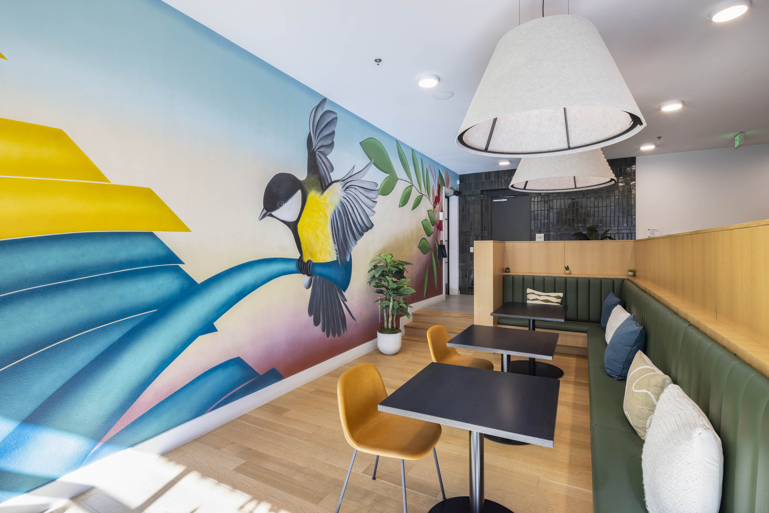 AMLI Branch Park apartments lounge with indoor mural of a yellow and black bird perched on a blue branch with greenery 