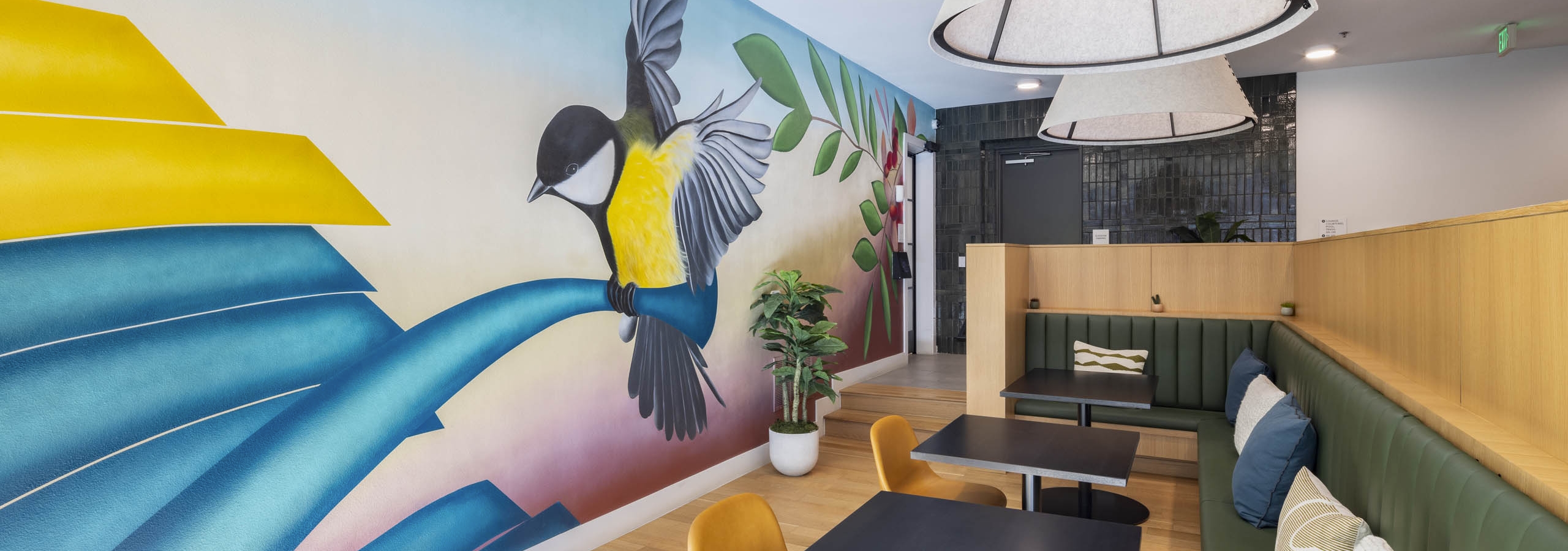 AMLI Branch Park apartments lounge with indoor mural of a yellow and black bird perched on a blue branch with greenery