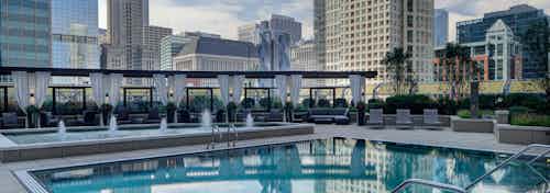 Evening view of the AMLI River North rooftop pool with surrounding lounge chairs and the Chicago skyline visible in the back