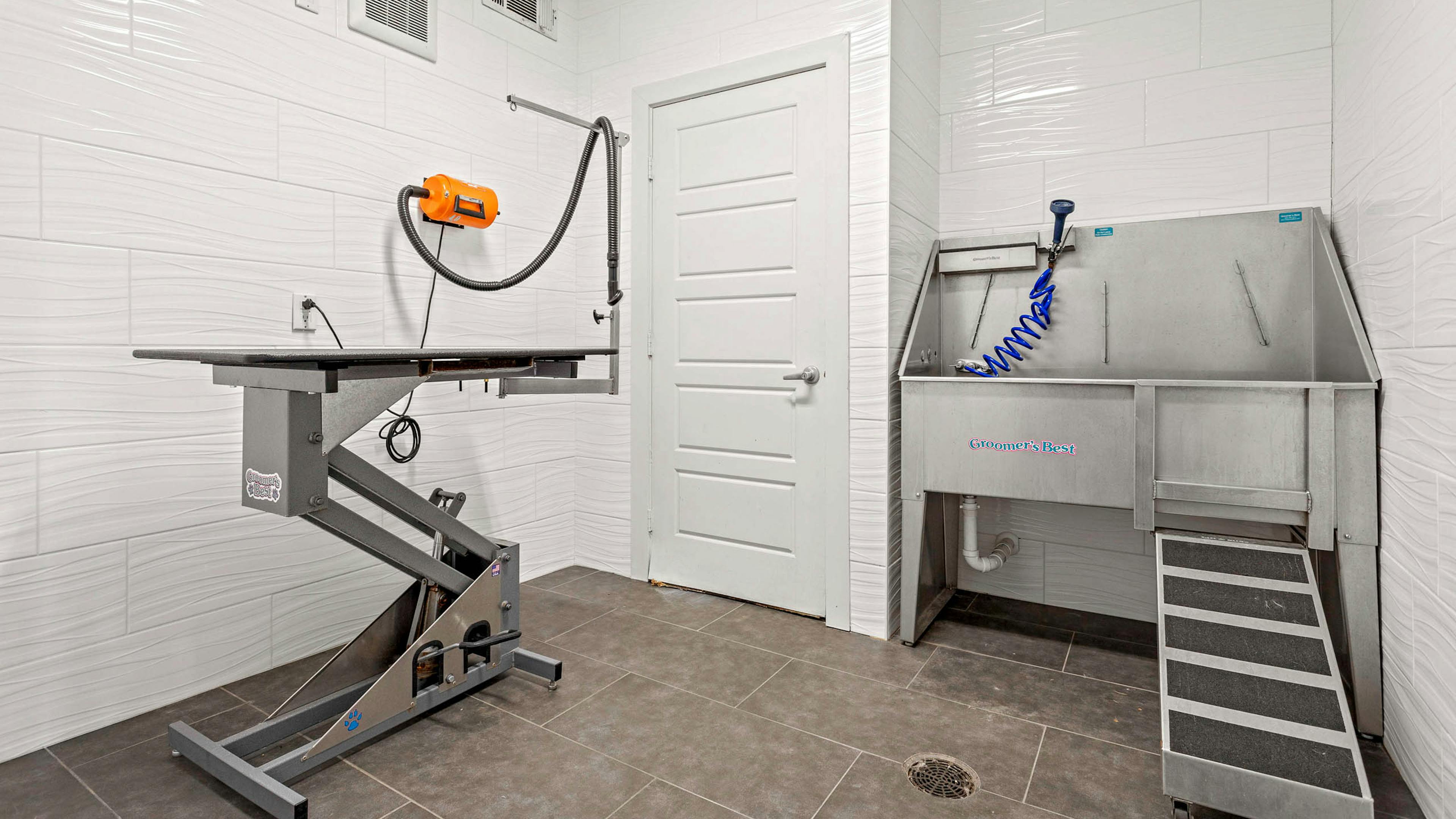 Indoor paw wash at AMLI at Escena apartments equipped with metal sink and drying station surrounded by white tiled walls