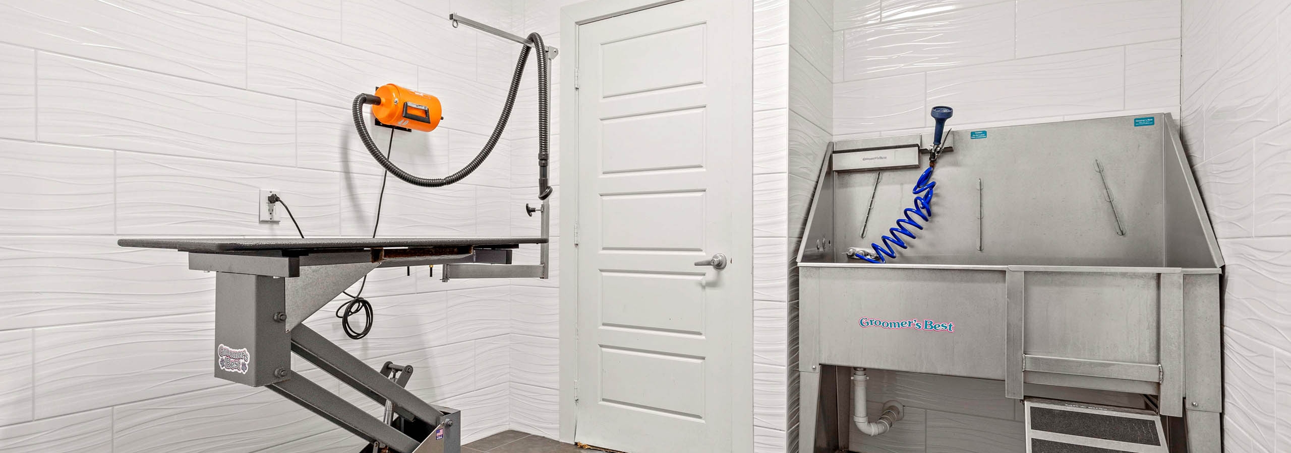 Indoor paw wash at AMLI at Escena apartments equipped with metal sink and drying station surrounded by white tiled walls