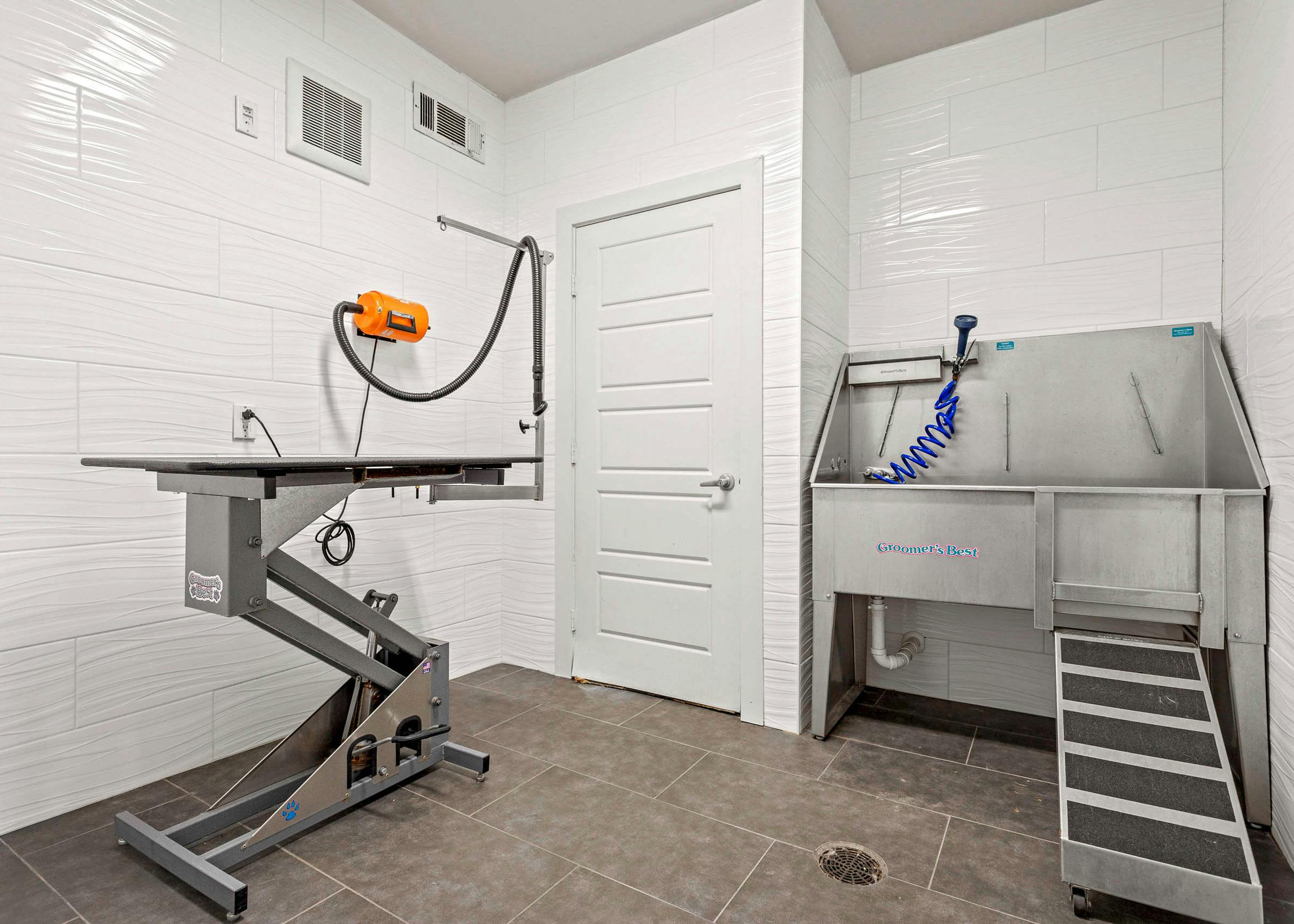 Indoor paw wash at AMLI at Escena apartments equipped with metal sink and drying station surrounded by white tiled walls