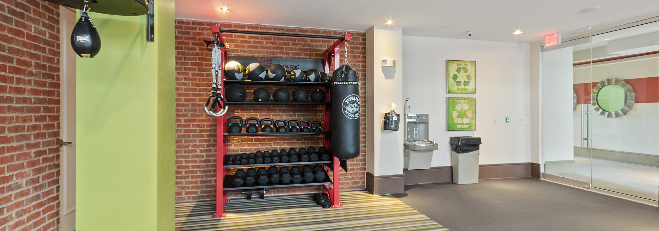 AMLI Ponce Park fitness center with red brick walls on striped carpet and dumbbells and medicine balls and punching bags