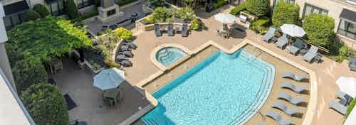 Aerial view of AMLI Las Colinas apartments courtyard pool and heated spa surrounded by lounge chairs and a grilling station