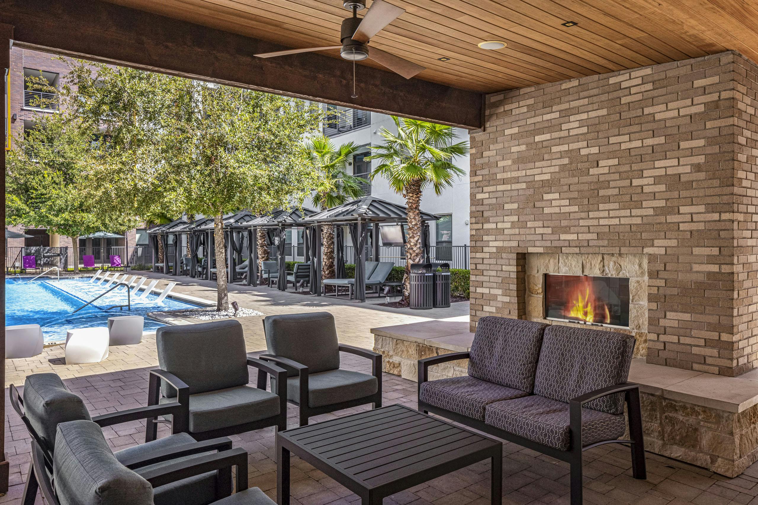 AMLI on Aldrich outdoor stone fireplace and seating adjacent to lounge seating and cabanas around the pool