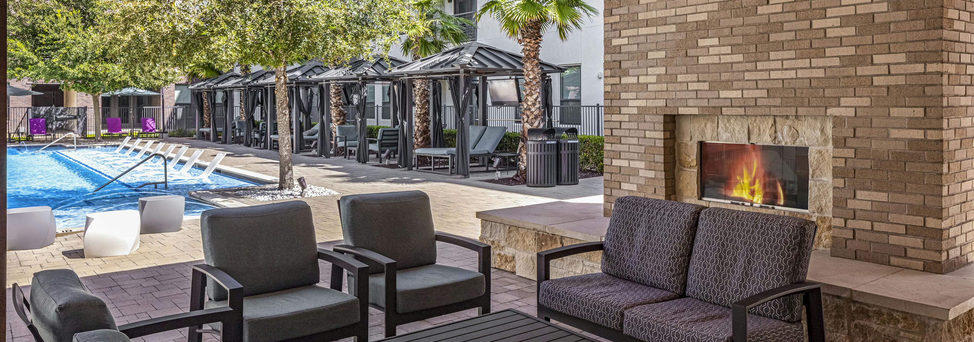 AMLI on Aldrich outdoor stone fireplace and seating adjacent to lounge seating and cabanas around the pool 