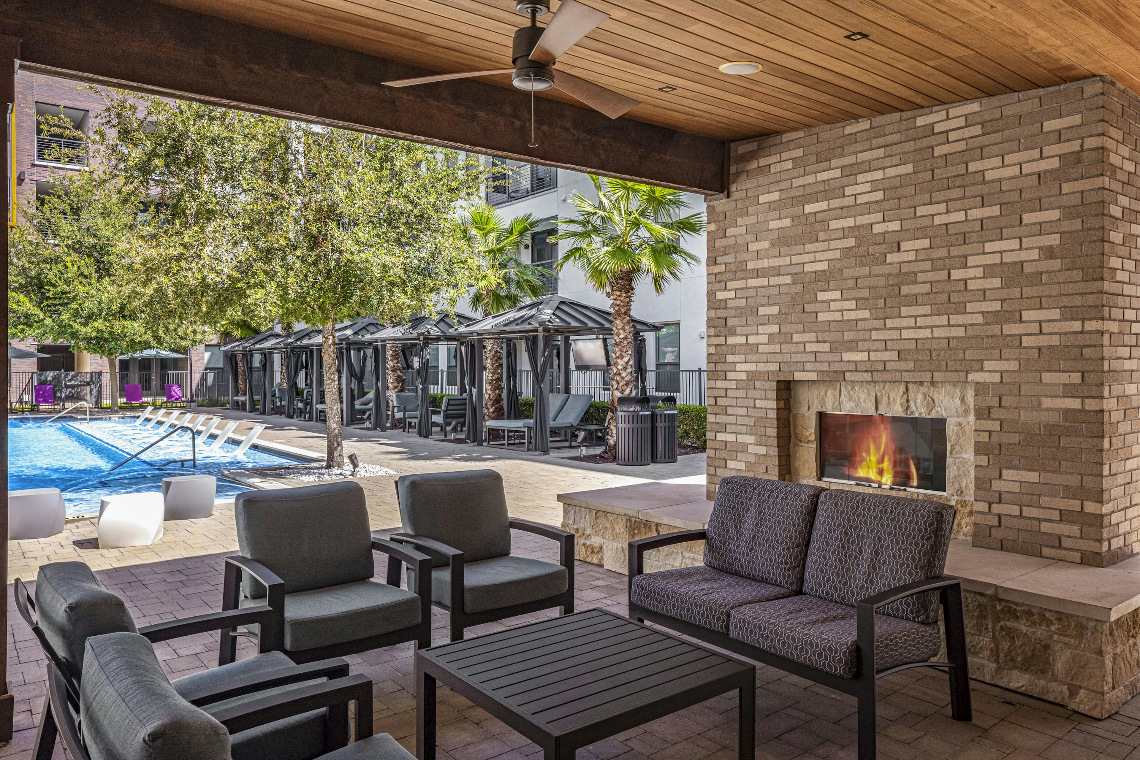 AMLI on Aldrich outdoor stone fireplace and seating adjacent to lounge seating and cabanas around the pool 