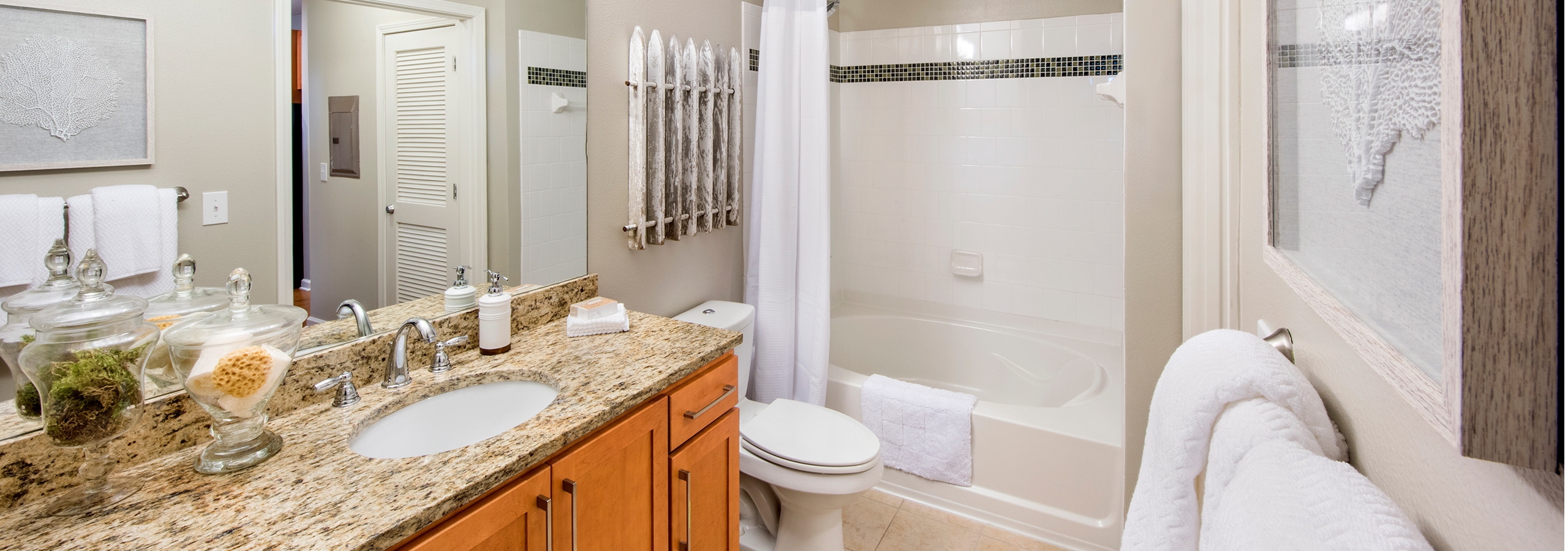 Interior view of AMLI North Point bathroom with a large granite vanity sink next to a toilet and a white tiled bathtub