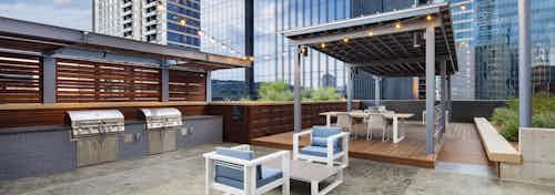 Outdoor grill area at AMLI on 2ND apartment building with two steel grills and a dining area shaded by a gray metal cabana