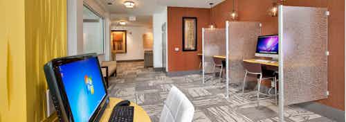 AMLI North Point business center which has multiple computers at individual desks against bold colored accent walls