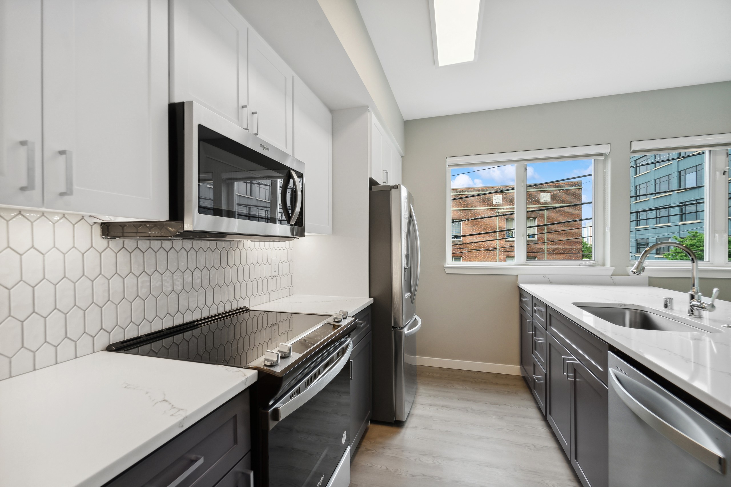 AMLI 535 kitchen with white cabinets above and gray cabinets below and white tile backsplash and stainless appliances