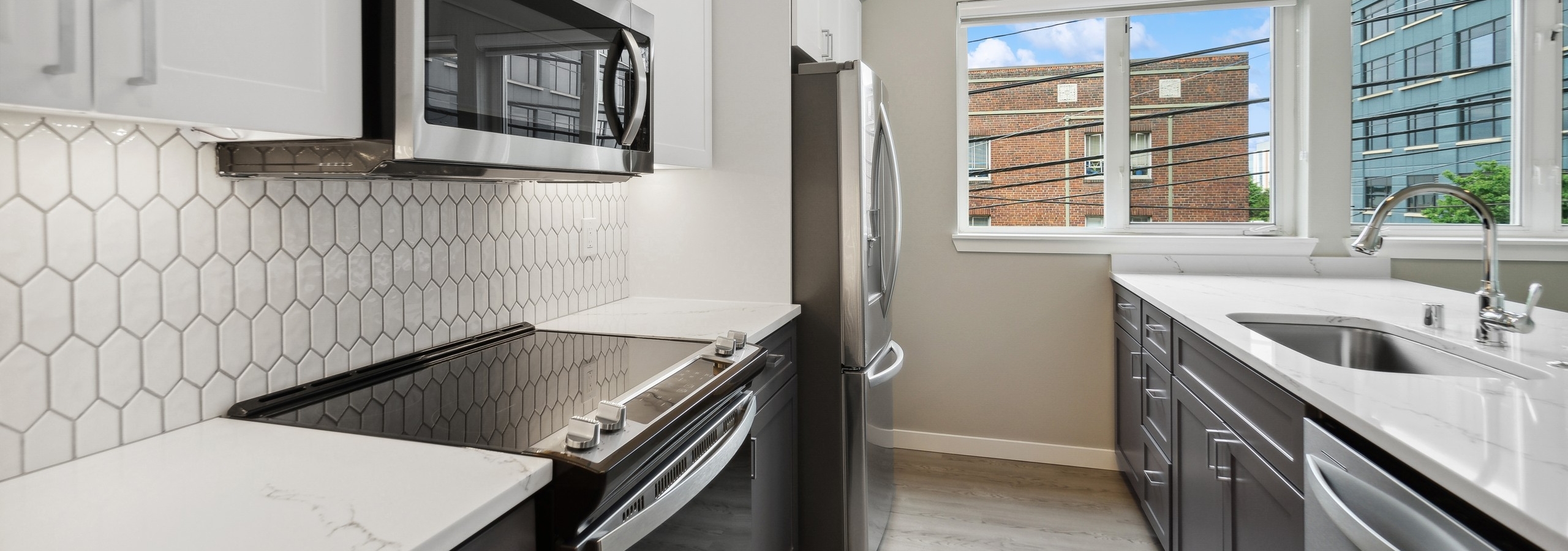 AMLI 535 kitchen with white cabinets above and gray cabinets below and white tile backsplash and stainless appliances