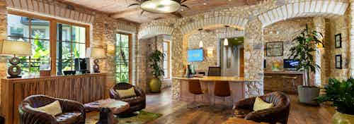 AMLI 300 leasing office with brick walls, a ceiling fan, wood-style flooring, brown leather lounge chairs, and plants