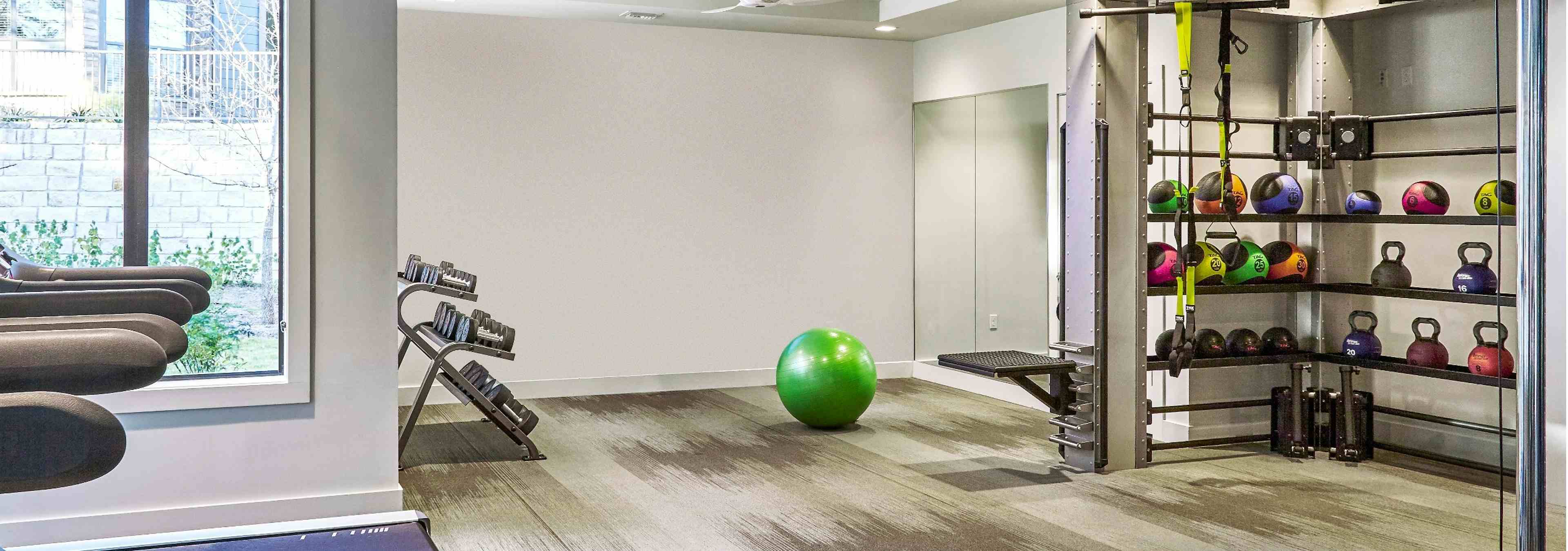 AMLI Covered Bridge free standing weight area with colorful weights, an exercise ball, and medicine balls