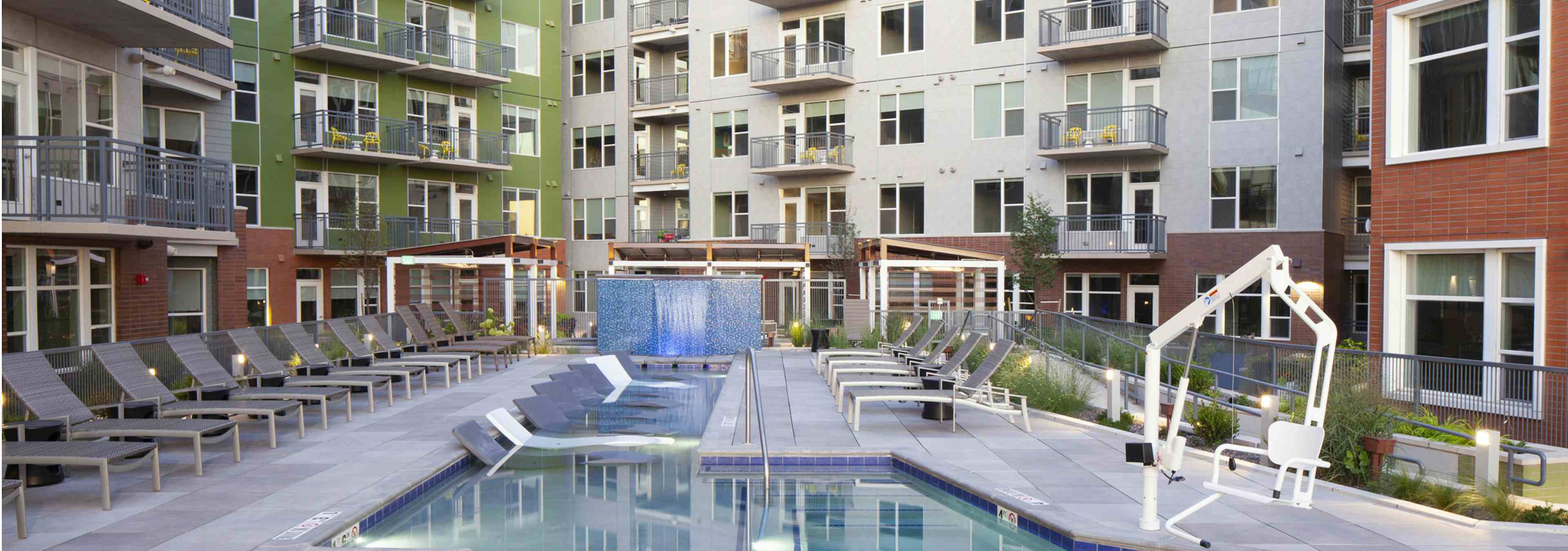 A daytime view of the pool at AMLI Riverfront Green apartments with a pool lift and apartment balconies in the background