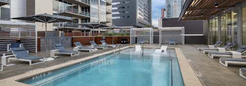 AMLI on 2ND apartments skye deck pool with gray lounge seating and gray umbrellas for shade and view of buildings